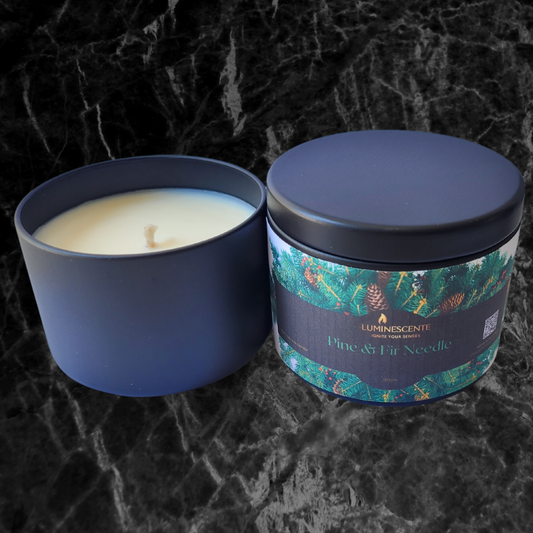 Soy candle with cotton wick in a black candle tin with lid. A colourful label of pine tree foliage on a black background with the Luminescente logo in gold.